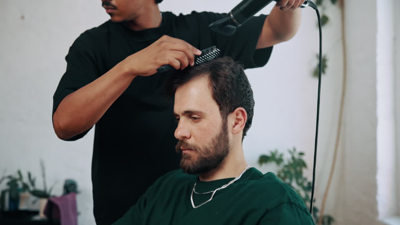 Barber Drying and Styling Man's Hair in a Modern Salon