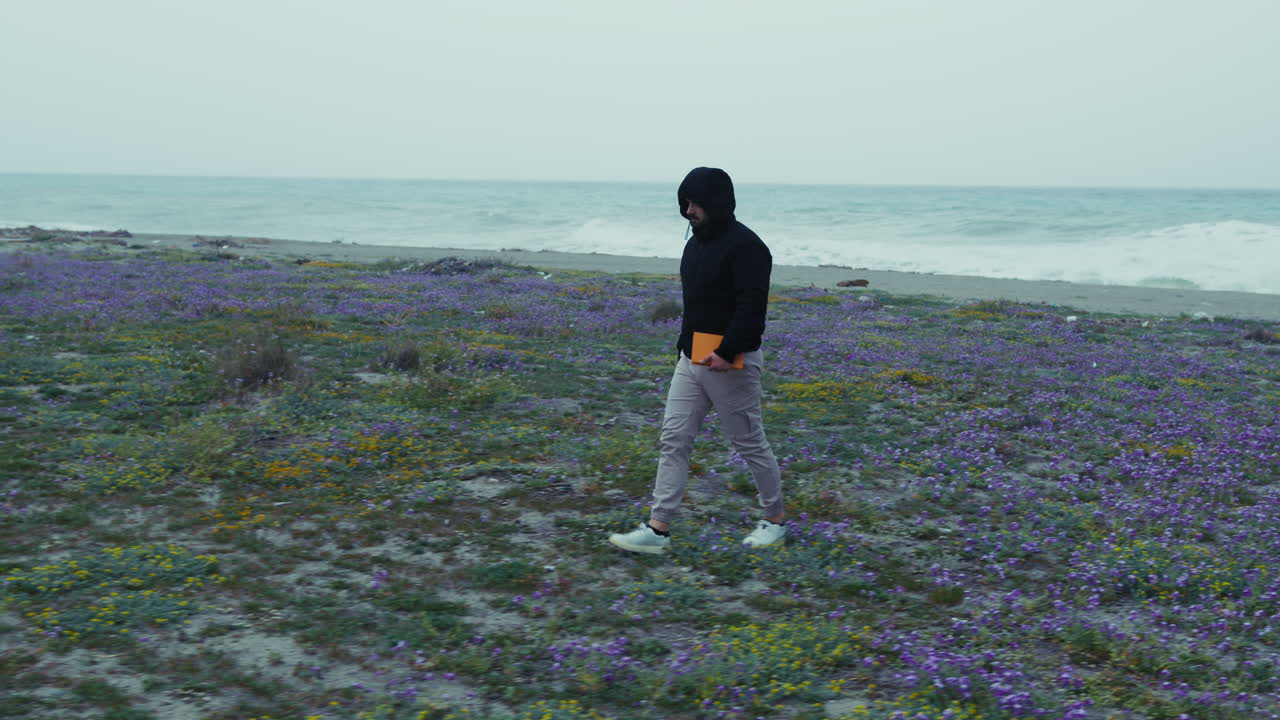 Man With Hoodie Walking Desolately On The Coast In Winter