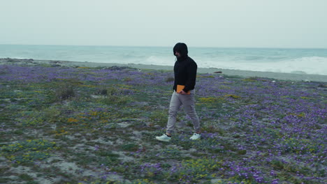 man with hoodie walking desolately on the coast in winter