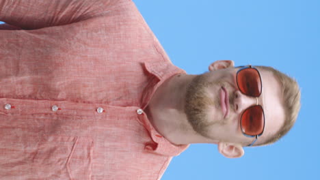 man adjusting sunglasses in a coral shirt