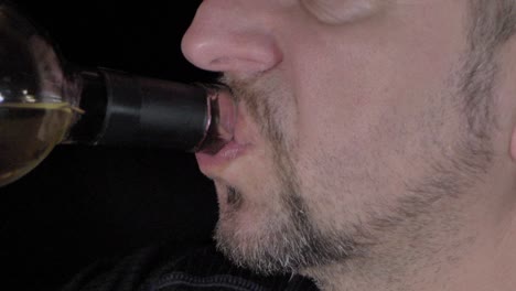 a man with a beard drinks wine from a bottle