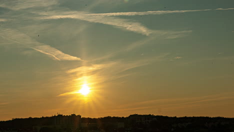 Una-Hermosa-Puesta-De-Sol,-Cuando-Se-Pone-El-Sol,-Un-Cielo-Mágico-Con-Nubes-Ligeras-Y-Un-Rastro-Del-Avión,-Pequeño-Movimiento-De-Cultivo