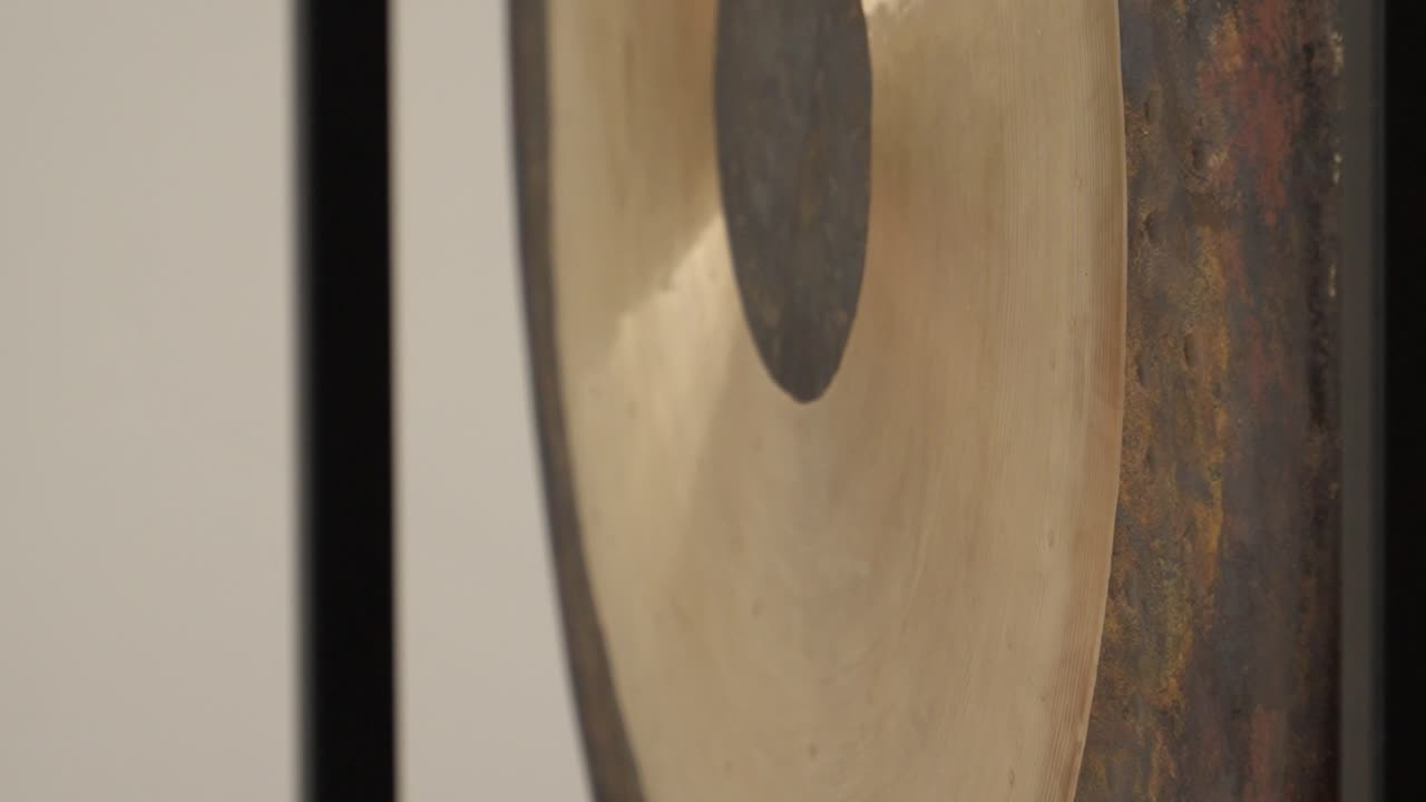 Slow motion footage of a gong being played, highlighting its deep vibrations