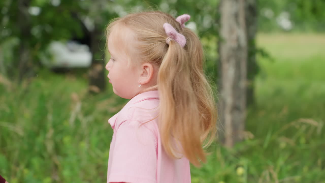 Madre caucásica abrazando a su hija en un prado, dulce beso en la mejilla, camiseta rosa y coletas, abedules y hierba alta, cálida luz de verano, abrazo cercano que muestra cuidado maternal y suaves sonrisas