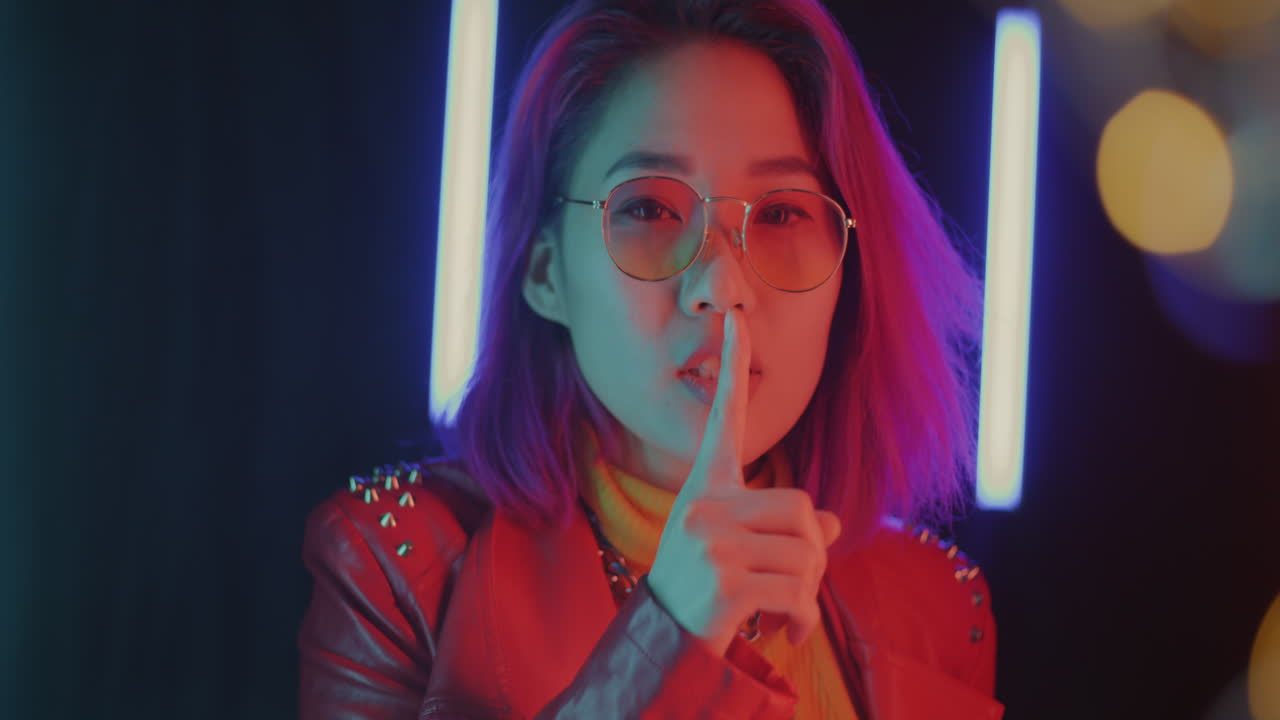 Elegante donna asiatica con capelli viola e giacca rossa sotto luce al neon