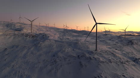 scenic drone shot of spinning wind turbines on snowy mountain against sunset sky