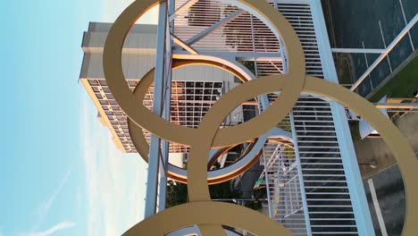 vertical panning shot of golden olympic rings on bridge in atlanta city at golden sunset