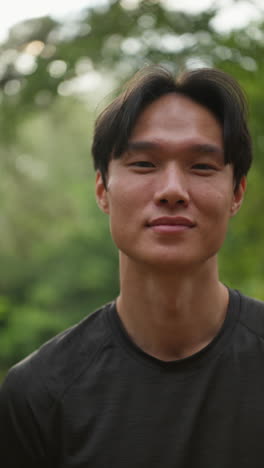 Vertical-Video-Portrait-Of-Smiling-Mid-Adult-Man-Exercising-Doing-Work-Out-Outdoors-In-Forest-Wearing-Sports-Clothing-Shot-In-Real-Time-1