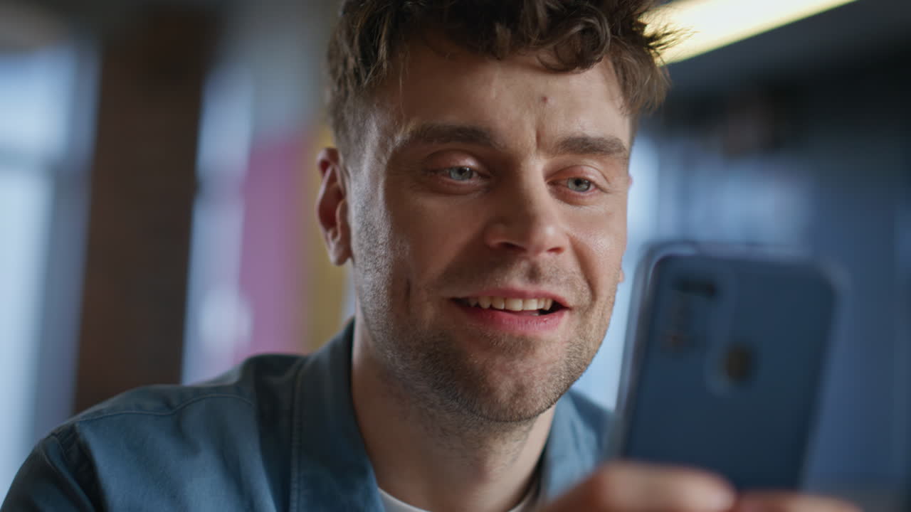 Smiling man watching smartphone in agency office closeup. Laughing businessman