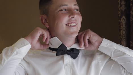 groom man adjusts bow tie, preparing to go to the bride, businessman in white shirt, wedding day