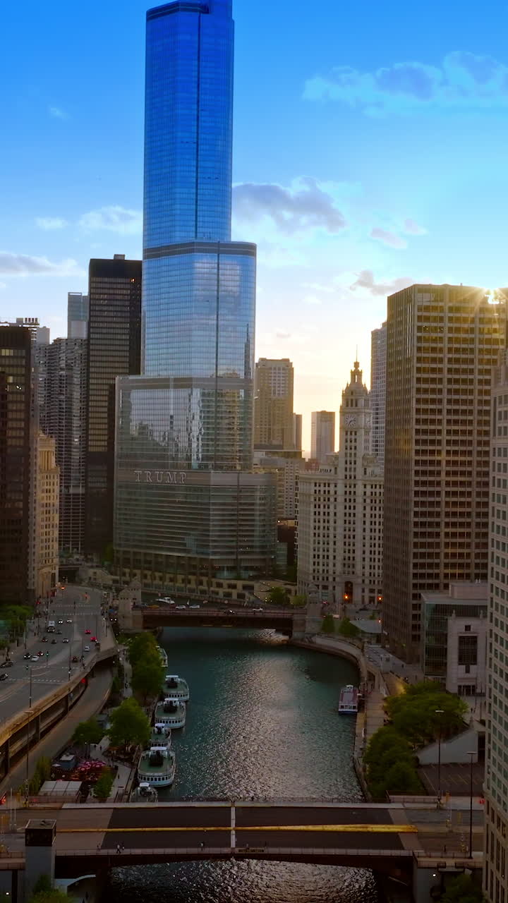Chicago downtown with futuristic architecture. River and bridges crossing it, multiple yachts on the water. Top view. Vertical video