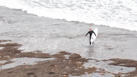 el surfista camina hacia formaciones rocosas icónicas