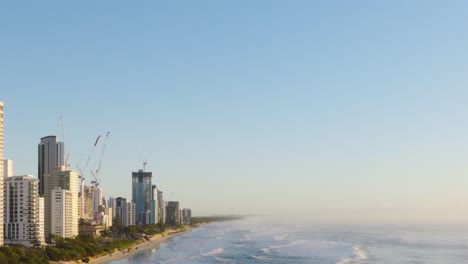 aerial footage of gold coast's skyline and ocean under clear blue skies, showcasing urban architecture and coastal beauty
