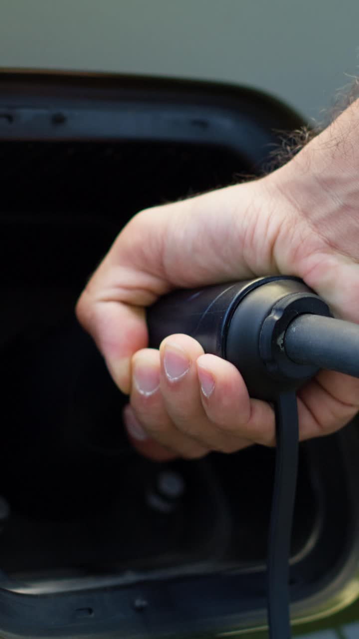 Vertical video Extreme closeup of eco conscious driver connecting electric car to charging port