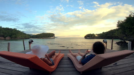 couple relaxing on a pier at sunset