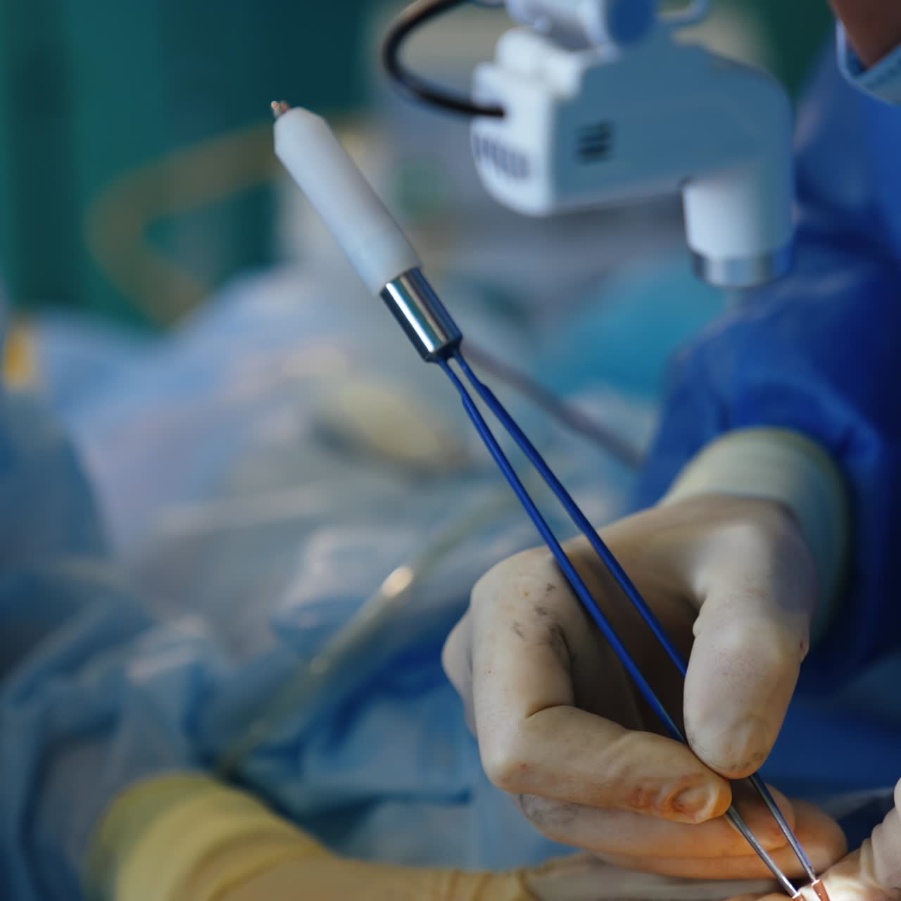 Precise work of a plastic surgeon. Breast implantation surgery in modern hospital. Doctor uses electric device. Nurse holding the patient's skin for the doctor