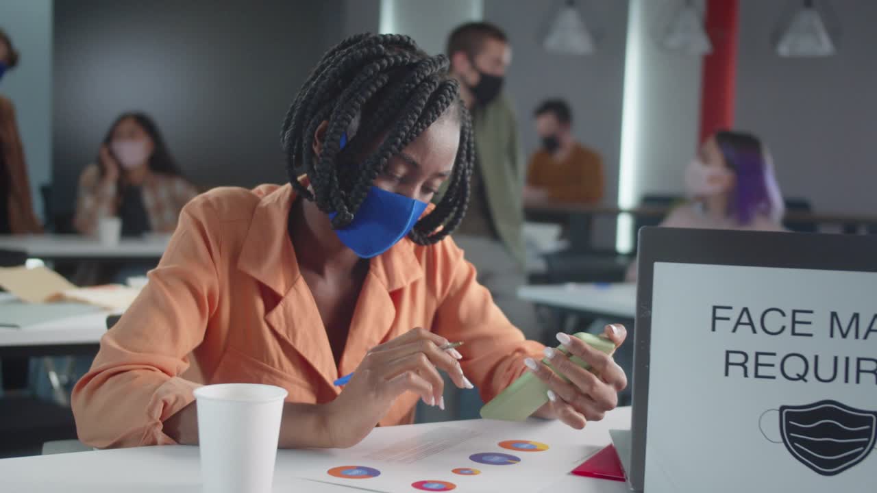 A handsome african professor is checking her students' homework and looking through the phone in the Internet, slow motion