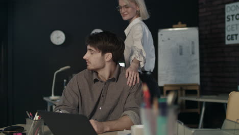 beautiful business woman whispering to ear young colleague at workplace.