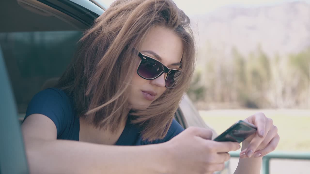 hermosa dama se desplaza por las redes sociales en el teléfono celular en el coche