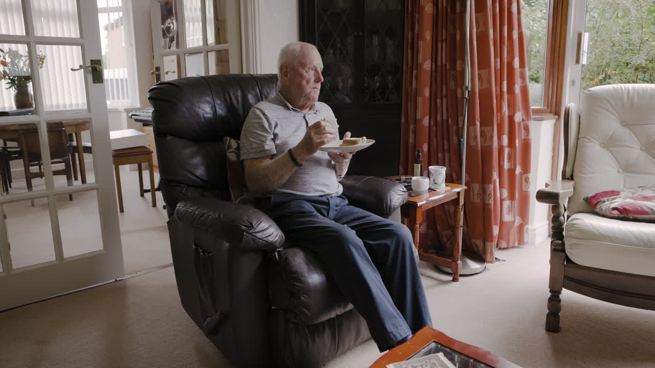 Senior man relaxing and eating in his living room