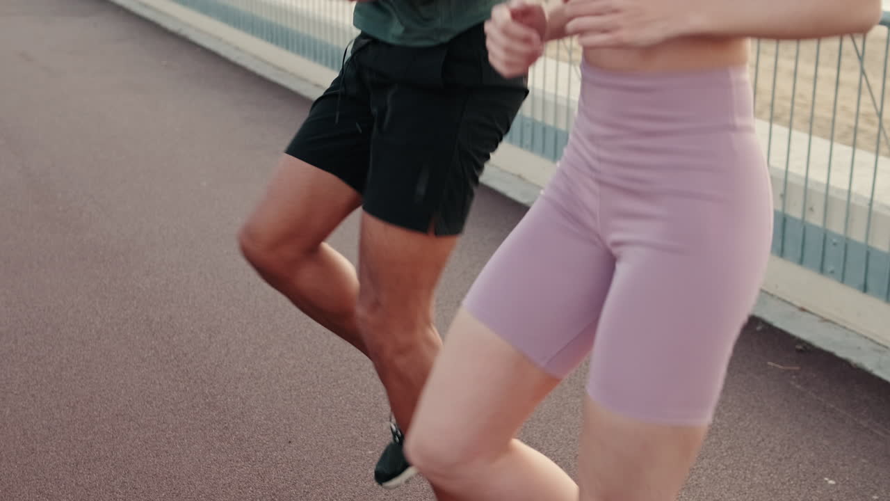 Coppia che si riscalda con l'esercizio a ginocchia alte su pista di atletica