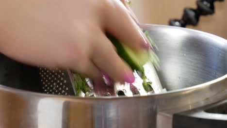 manos femeninas rallando pepino fresco en vista estática