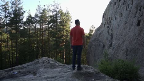 turista mirando a su alrededor y a la formación rocosa natural de la roca del águila o también llamada la orlovi skali, ubicada en la montaña rhodope en bulgaria