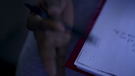 a hand taps a pen against a page in a notebook.