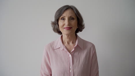 Happy-Senior-Woman-Jumping-And-Cheering-While-Looking-At-Camera-On-White-Background