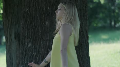 woman in yellow dress dancing by tree in summer park