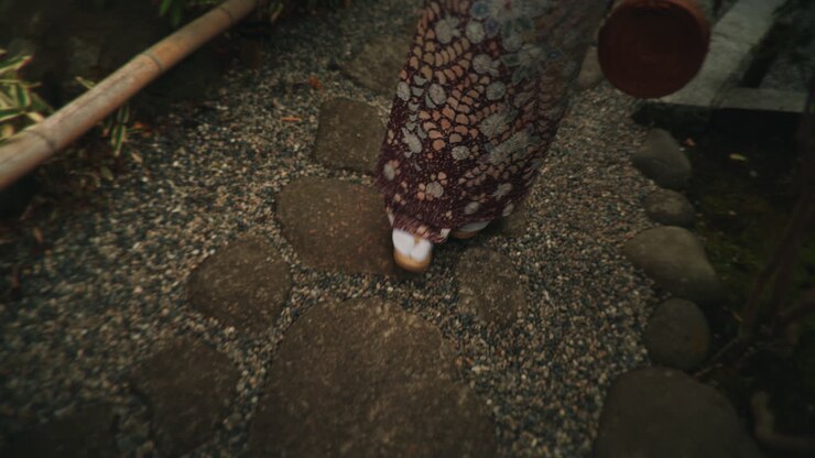 Persoon in kimono die over een tuinpad loopt