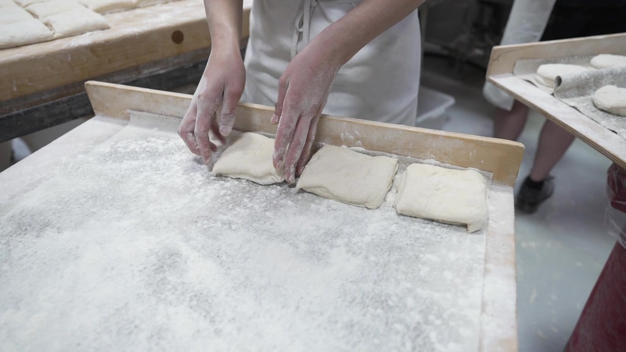 A woman rolling dough in a private bakery, captured in 4K resolution at 60fps, slow motion.