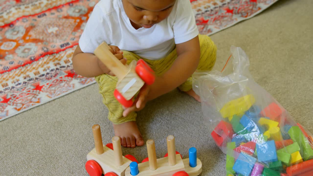 vista de alto ángulo de un lindo niño negro jugando y agachado en el suelo de una casa cómoda 4k