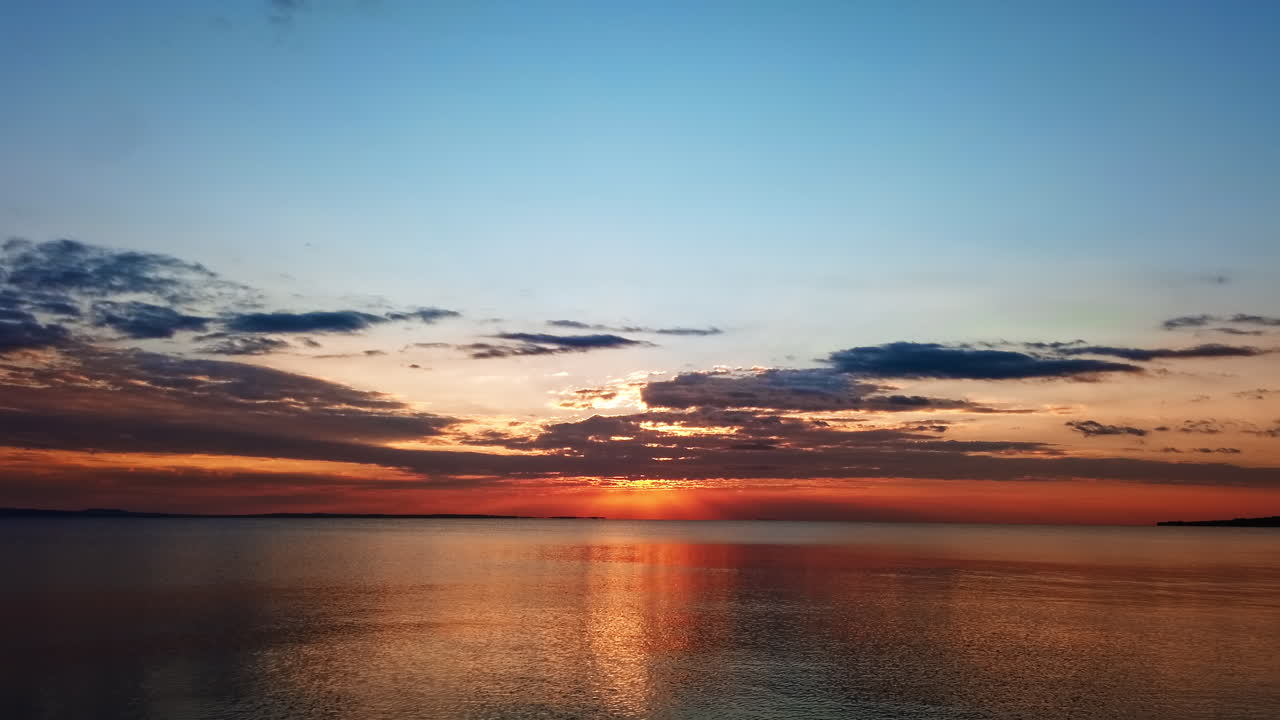 Solnedgang over Det Ægæiske Hav. Sol, land i det fjerne, refleksioner i vandet, Grækenland