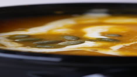 close-up of a bowl of pumpkin soup with cream and pumpkin seeds