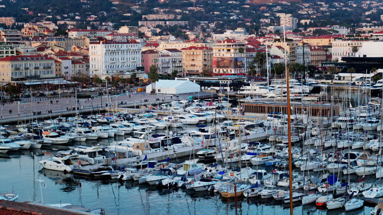 Cannes, Francia - 15 marzo 2025: vista di diverse barche ormeggiate nel porto turistico di Cannes con gli edifici della città sullo sfondo al tramonto