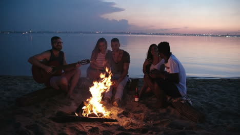 group of friends sitting on the beach at dusk