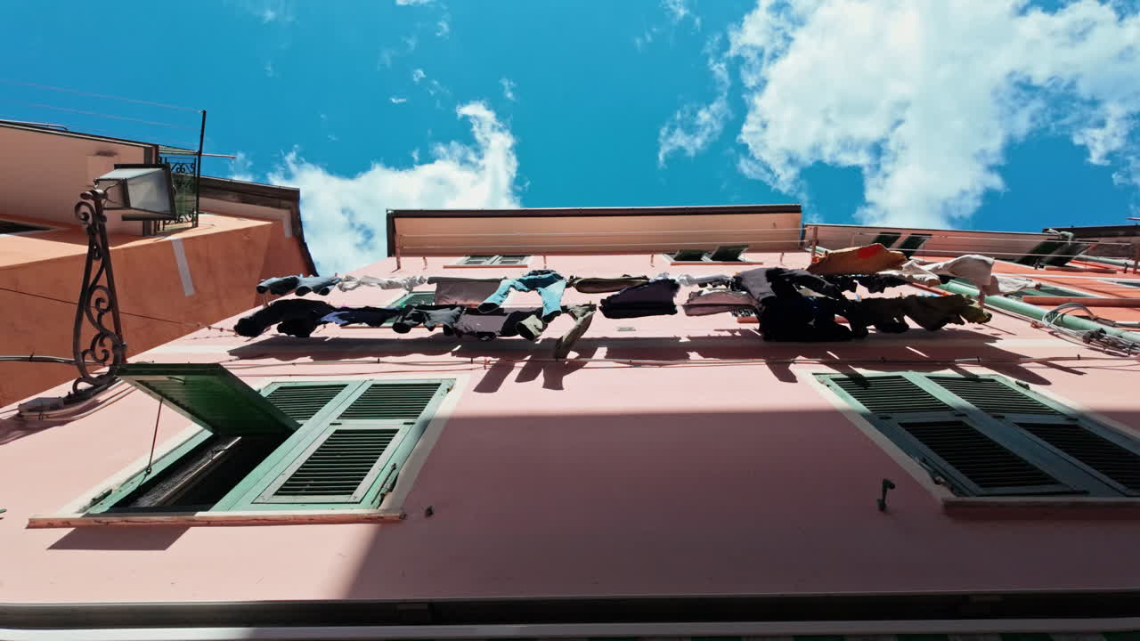 Pink house in Vernazza, Cinque Terre with colorful laundry hanging under the sky