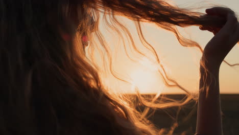 young woman looks at her hair in the sun, holds a lock of hair in her hand