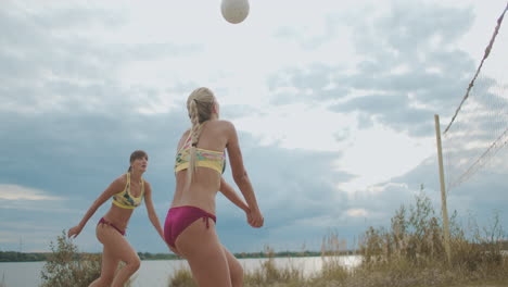 professional beach volleyball female players are training on sand court at summer passing and attacking other team