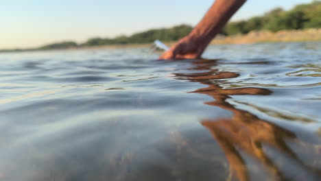 male hand filling a caraf full of fresh water from a river - slow motion shot