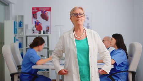 Portrait-of-elderly-doctor-standing-in-front-of-camera-smiling