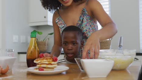 video of african american mother and son cooking together in the kitchen