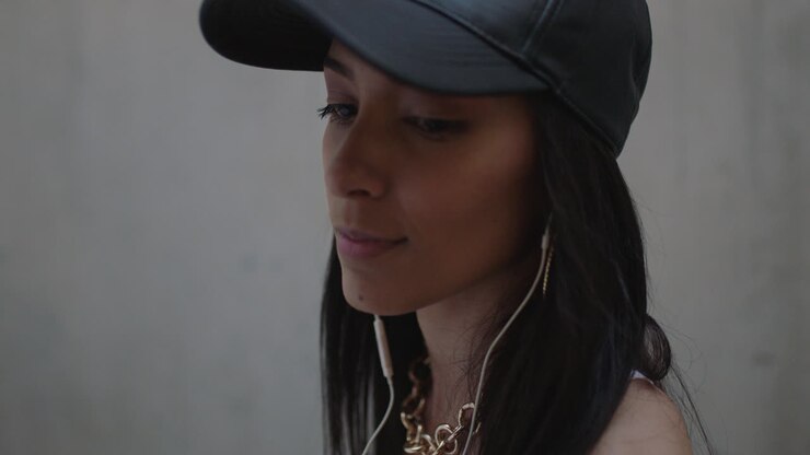 portrait confident young mixed race woman wearing earphones enjoying listening to music wearing trendy fashion