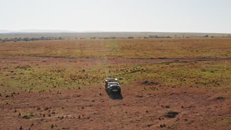 Aerial-drone-shot-of-Wildlife-Photographer-Driving-Safari-Vehicle-in-Maasai-Mara-National-Reserve-Savanna,-Kenya,-Africa-with-Beautiful-Landscape-Scenery,-Masai-Mara-North-Conservancy