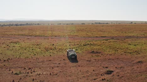 aerial drone shot of wildlife photographer driving safari vehicle in maasai mara national reserve savanna, kenya, africa with beautiful landscape scenery, masai mara north conservancy