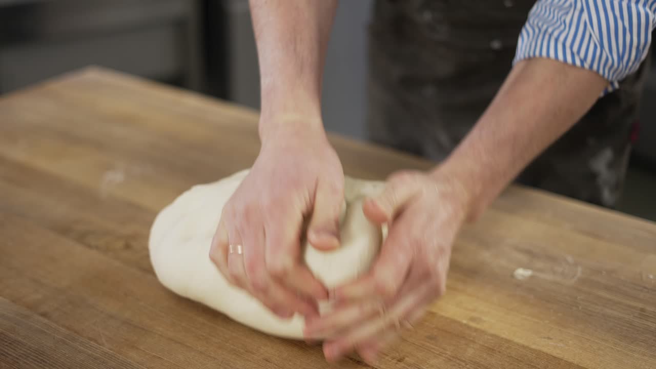 Close Up shot of hands of senior bakery chef applying flour on dough, aged man kneading dough, making bread using traditional