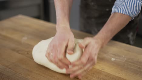 Close-Up-shot-of-hands-of-senior-bakery-chef-applying-flour-on-dough,-aged-man-kneading-dough,-making-bread-using-traditional