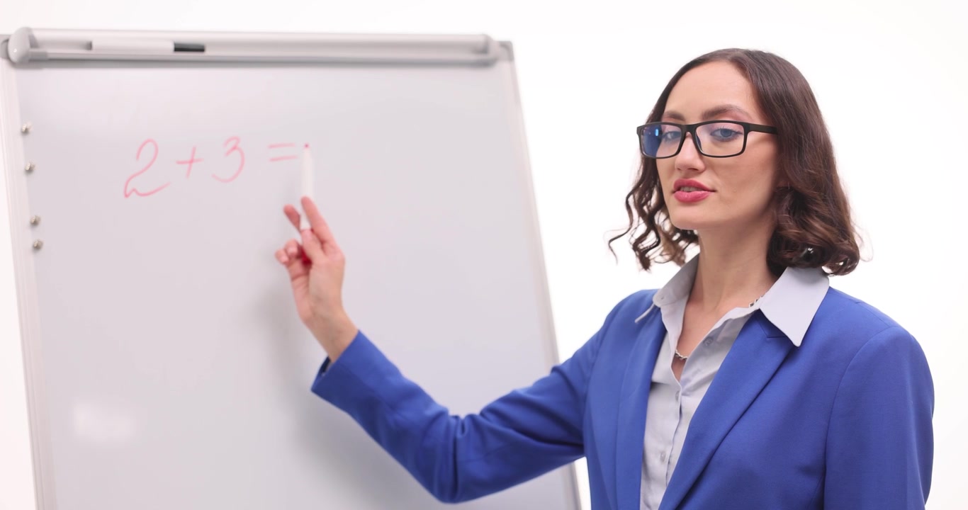 Una donna indica con una penna una lavagna bianca con un semplice problema di matematica
