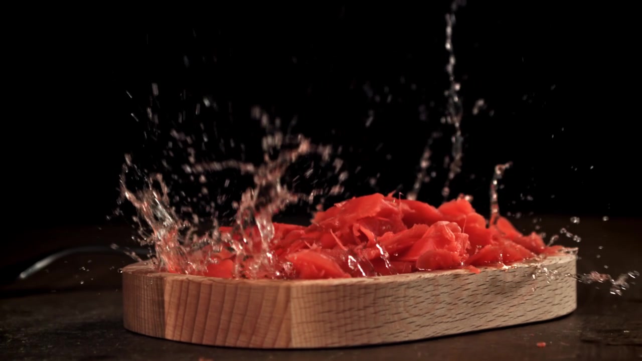 Red Pickled Ginger Splashing on Wooden Board in Slow Motion